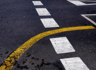 Stra&szlig;enmarkierungen mit gelber und wei&szlig;er Farbe auf schwarzem Asphalt