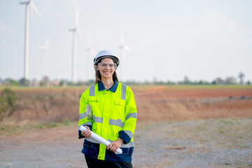 Pretty engineer or technician woman worker hold drawing paper and look at camera with smiling also stand in front of windmill cluster in workplace. - Powered by Adobe