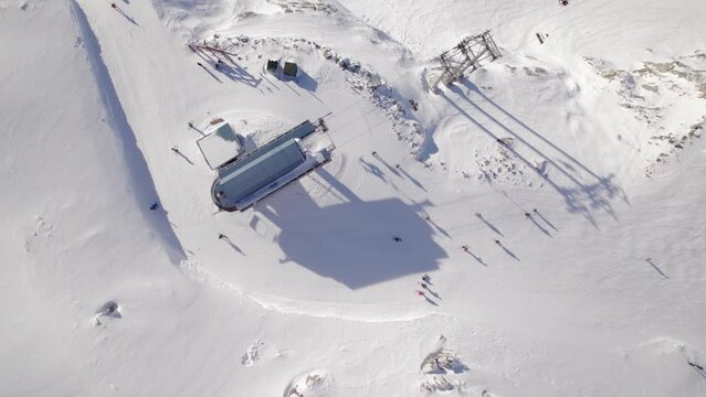 Top down of chairlift, aerial drone footage ski hill on a sunny day, Whistler BC, ski run, skier, winter sport. 4K 24FPS.