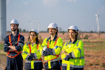 Fototapeta premium Group of engineer or technician workers stand in a row with arm-crossed and look to right side also smiling and stand in front of windmill cluster.