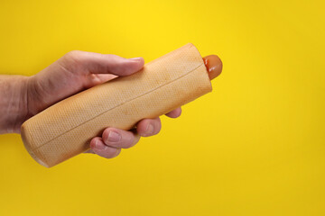 french hot dog with ketchup sauce in hand on yellow background