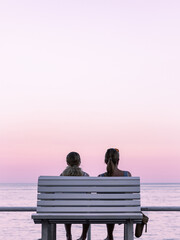 Deux femmes contemplent la mer Méditerranée sur la promenade à Nice au coucher du soleil.