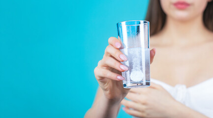 Woman taking drugs to releave headache. Brunette take some pills, holds glass of water, isolated on...