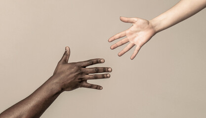 Helping hands, Rescue gesture. Black and white human hands. African and caucasian hands. Giving a...