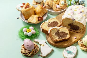 Obraz na płótnie Canvas Festive dinner, Easter brunch. Happy Easter holiday food baking puff pastry and cupcake with Easter Bunny on pastel green background. Copy space.