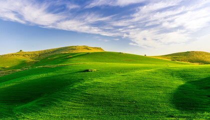 scenery rural view of a contryside farm in green fields and hills with amazing cloudy sky on background