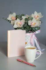 Flowers, tea and a pink diary. Bouquet of flowers from eucalyptus and white orchids. Morning blogger.