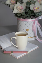 Flowers, tea and a pink diary. Bouquet of flowers from eucalyptus and white orchids. Morning blogger.