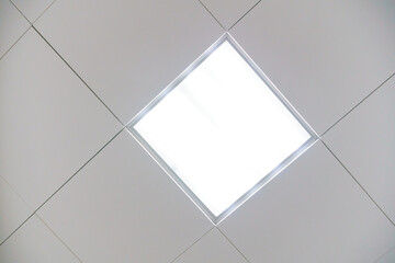 Square lamp on a white office ceiling. Interior design in the office. A fluorescent lamp on a modern suspended ceiling.