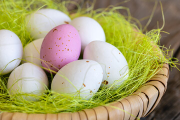 Easter candies, colorful chocolate eggs in a nest on a wooden background, the concept of the Easter holiday, a traditional dessert for children.
