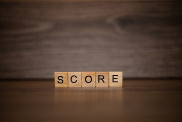 The word score is made up of wooden cubes tablets on a dark wooden background