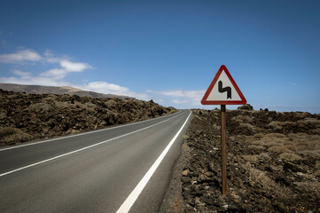 Empty road with bend sign on the Island of Lanzarote, Canary Islands Spain
