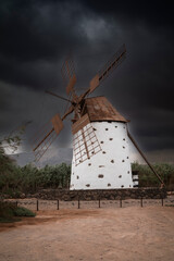 Widoki z wulkanicznej hiszpańskiej wyspy Fuerteventura. Wiatrak na tle burzowego i pochmurnego nieba. Krajobrazy wysp kanaryjskich. Biała architektura. Fotografia podróżnicza.  © anettastar