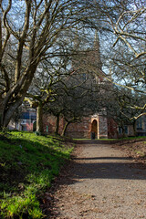 Fototapeta premium Pretty Red stone church of St Mary in a Devon town. Capture shows the path leading to the doors in wintertime. 