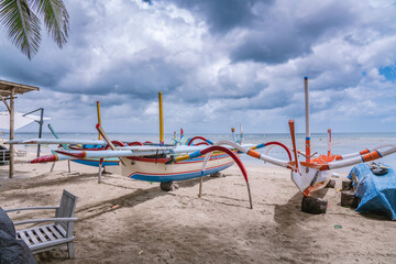 Traditional Balinese boats in different colors on Sanur beach in Bali, Indonesia. Sea side at background