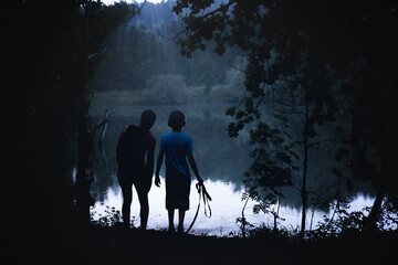 Two children come out of the dark forest to the river bank. The concept of lost children