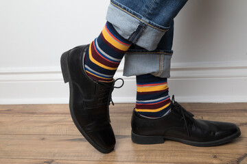 Product photo of men's colourful socks, black dress shoes, and jeans. 