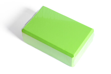 A green foam yoga block isolated on a white background. Concept of fitness equipment.