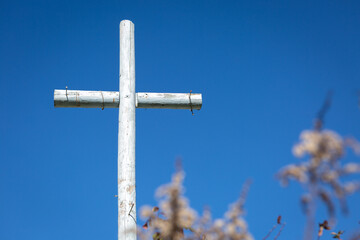 Rustic painted wooden cross with nails in garden 