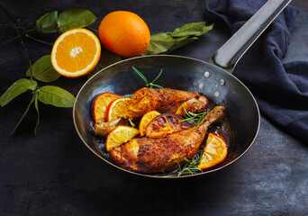 Traditional barbecue chicken drumsticks with orange slices served with herbs as close-up on a...
