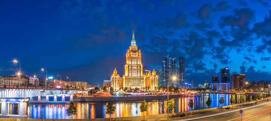 Illuminated high-rise stalinist building near river at summer night in Moscow, Russia. Historic...