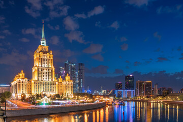 Illuminated high-rise stalinist building near river at summer night in Moscow, Russia. Historic...