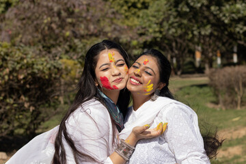 Two young girls sisters friends family celebrating enjoying holi festival of colors colours outdoor in a park a popular hindu festival celebrated across india with gulal abeer color powder