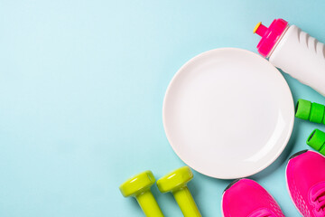 Dumbbells, white plate and sport shoes on blue. Healthy lifestile, fitness, diet and weight loss concept.