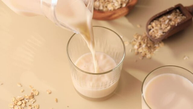 Oatmeal vegetarian milk is poured into a glass from a jug. Alternative milk