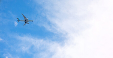 View of airplane flying in blue sky among white clouds. Banner, copy space. High quality photo