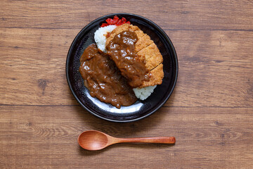 テーブルの上の黒い皿に盛ったカツカレー