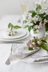 Obraz na płótnie Canvas Beautiful table decor for a wedding dinner with a spring blooming apple tree flowers. Celebration of a special event. Fancy white plates, wineglasses