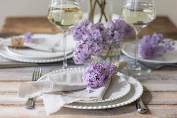 Schilderijen op glas Beautiful table decor for a wedding dinner with a spring blooming lilac flowers. Celebration of a special event. Fancy white plates, wineglasses. Countryside style © ArtSys