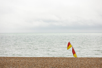 Fototapeta na wymiar Hastings, united kingdom, 24, August 2022 Lifeguard flags blowing in sea breeze marking safe swimming area,