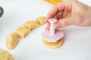 The process of making cookies with shapes in the form of flowers, a rolling pin and a tray, the concept of cooking, baking at home.