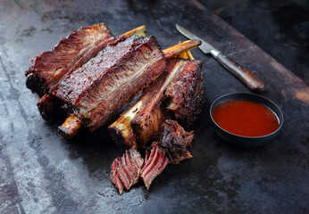 Traditional barbecue burnt chuck short beef ribs marinated with spicy rub and served with a hot chili sauce as close-up on a rustic board