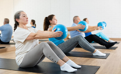 People of different ages clutching Pilates ball in hands during group workout. Active lifestyle and wellness concept
