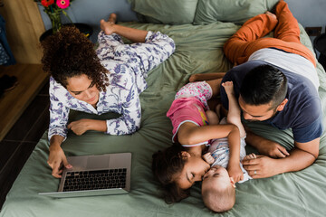 Happy hispanic family laughing and having fun together on the bed at home in Mexico Latin America