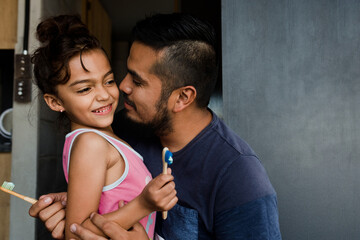 hispanic Father teaching daughter how to brush teeth at home in Mexico Latin America