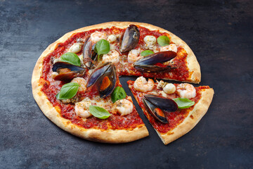 Traditional Italian pizza frutti di mare with king prawns, blue mussels and calamaretti served as close-up on a rustic board