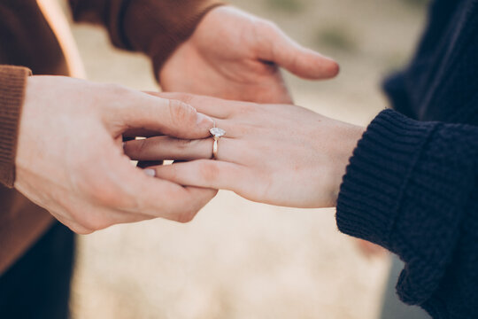 hands of a man and woman after a proposal with close up of a simple diamond ring