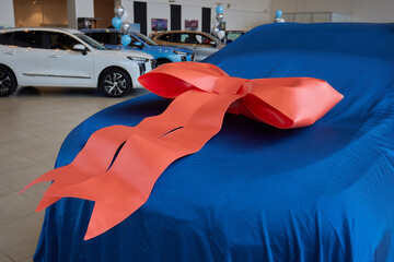 The new car is wrapped in a red bow. Beautiful gift concept.
