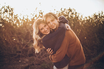 couple hugging in a field embraced in a hug and smiling in the golden light