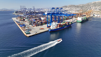 Aerial drone photo of huge fully loaded container tanker ship reaching with help of tug boat...