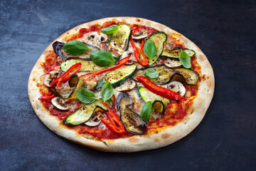 Traditionelle italienische Veggie Pizza mit Aubergine, Pilzen und Zucchini serviert als close-up auf einem alten rustikalen Board mit Textfreiraum 