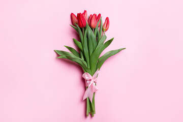 Bouquet of tulips on a pink background. With a pink bow