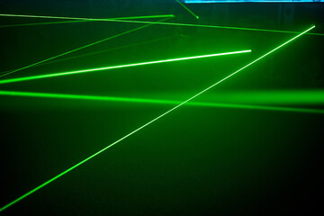 Bright green neon laser lights illuminate the darkness creating lines and triangle shapes in sci-fi effect. - obrazy, fototapety, plakaty