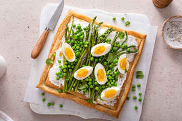 Fresh spring tart with green peas and asparagus on puff pastry