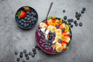 Healthy summer acai smoothie bowl with chia seeds, fresh banana, strawberry, blueberry, cocos, kiwi...