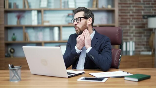 Sad mature business man investor with severe toothache suffers from strong pain ache sitting at desktop in workplace office Unhealthy entrepreneur bothered by sore tooth while typing on laptop indoor